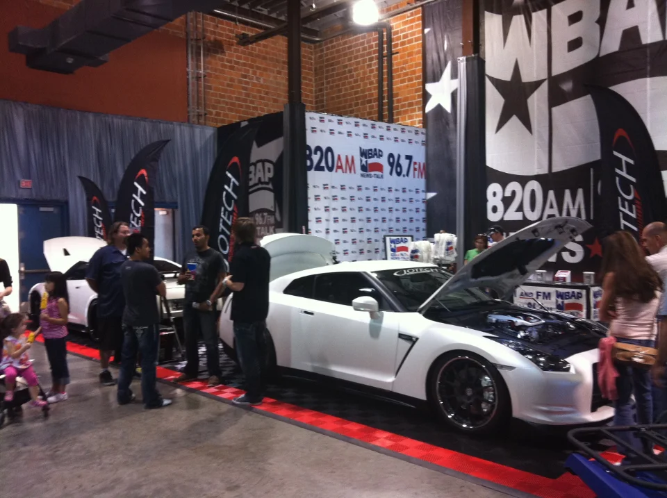 White Nissan GT-R on display at a car show event with people gathered around, featuring Jotech Motorsports branding.