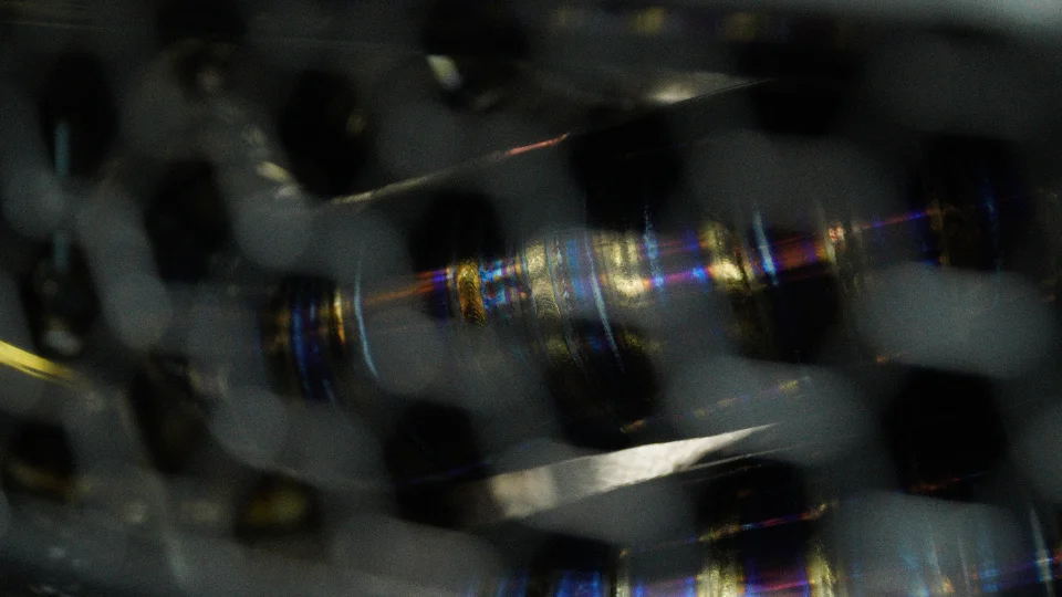 Close-up detail of a heat-treated titanium exhaust component with iridescent colors and reflections.