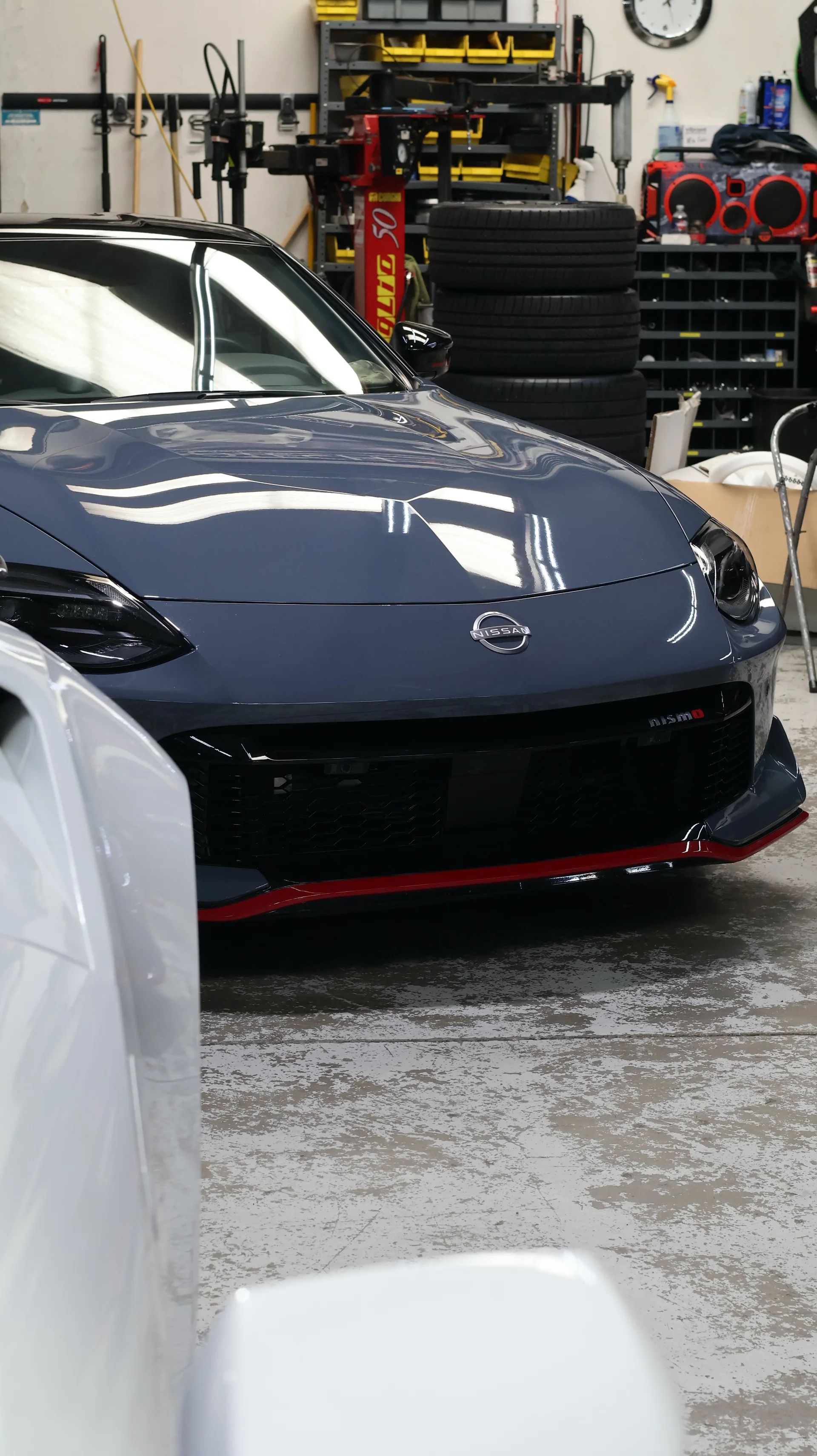 Front view of a gray Nissan Z Nismo with a red splitter in a performance tuning shop.