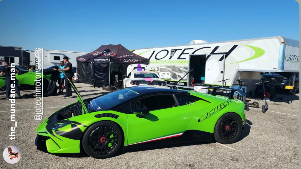 A bright green Lamborghini Huracan with its hood open, parked next to a Jotech Motorsports trailer and tent at a track event.