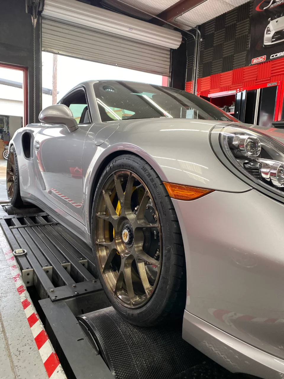 Silver Porsche 911 on a dynamometer with bronze aftermarket wheels and yellow brake calipers.