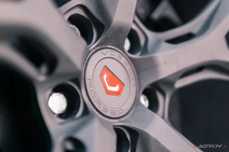 Close-up of a grey Vossen wheel with a red Vossen logo on the center cap and visible lug nuts.