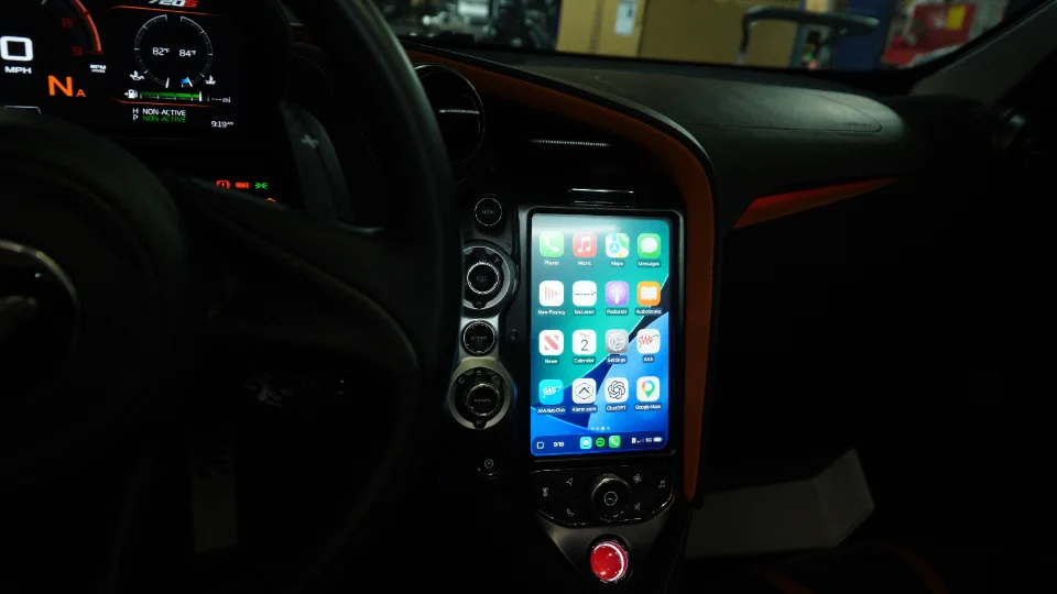 Interior view of a McLaren 720S dashboard showing a custom vertical infotainment screen displaying an Apple CarPlay interface.