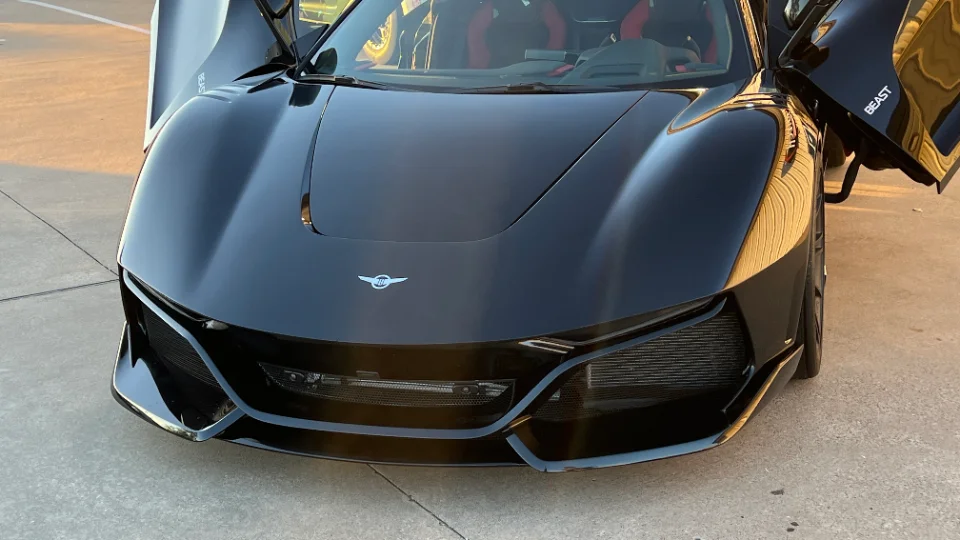 Front view of a black Rezvani Beast supercar with its doors open, parked outdoors.