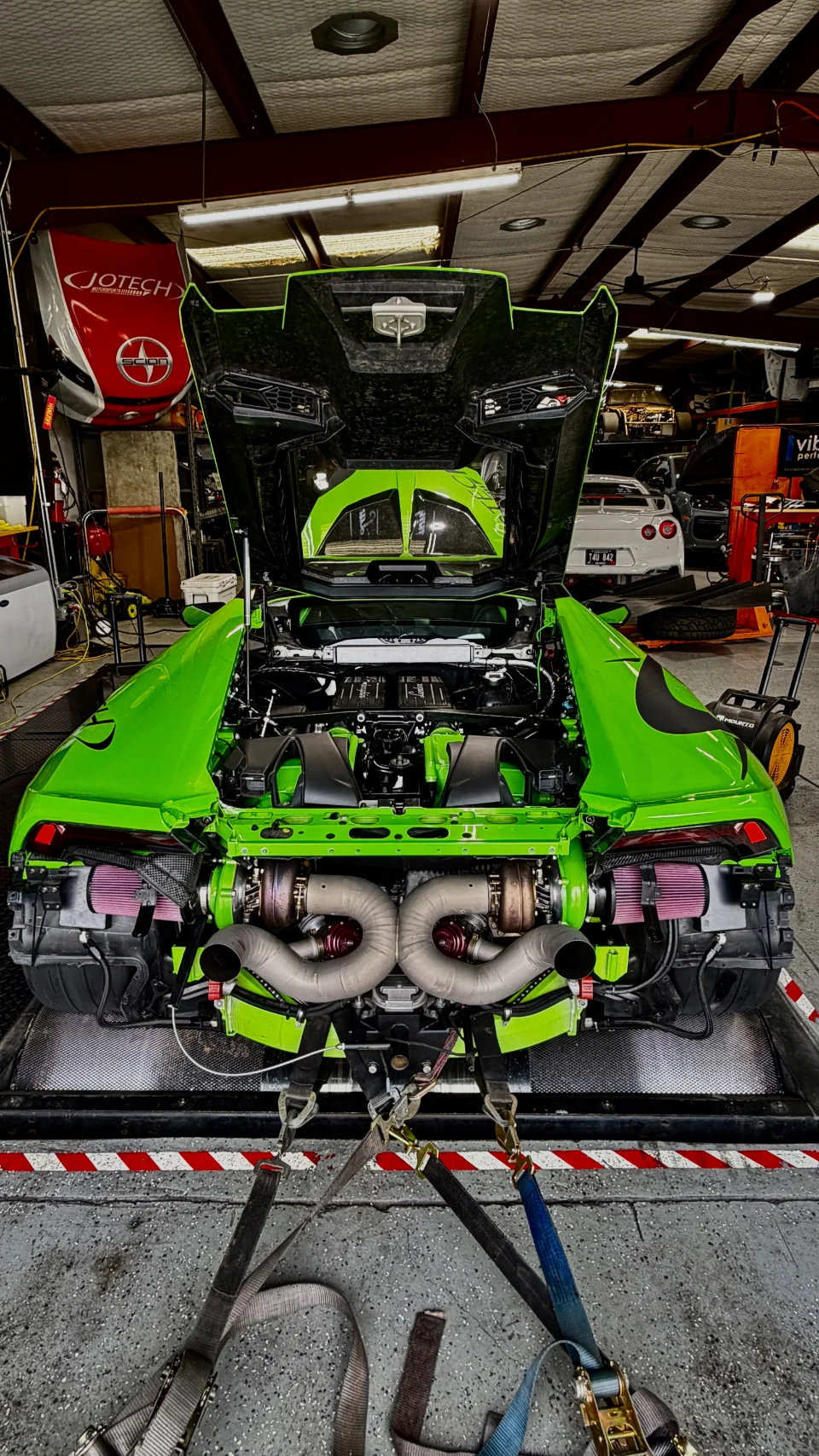 Bright green Lamborghini Huracan on a dyno, showcasing its twin-turbo engine setup at a performance shop.