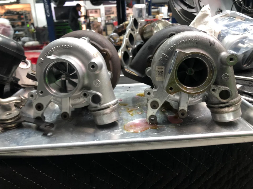 Two new turbochargers on a metal tray in a performance tuning shop, ready for installation.