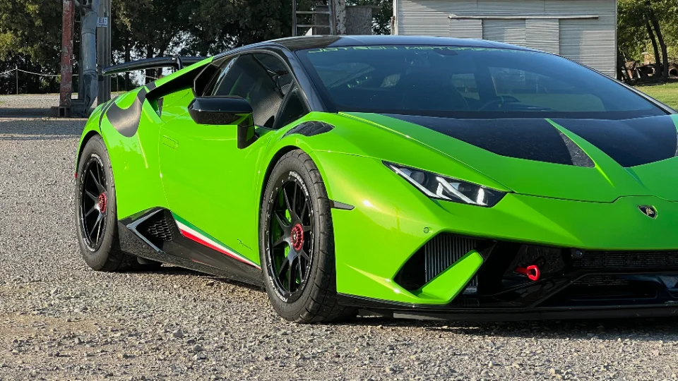 A green Lamborghini Huracan with Forgeline wheels and a rear wing parked on gravel, showcasing Jotech Motorsports branding.
