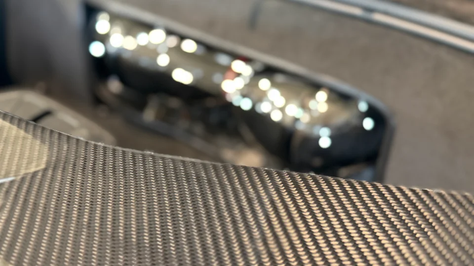 Close-up of carbon fiber interior trim in a performance car, showcasing the weave pattern.