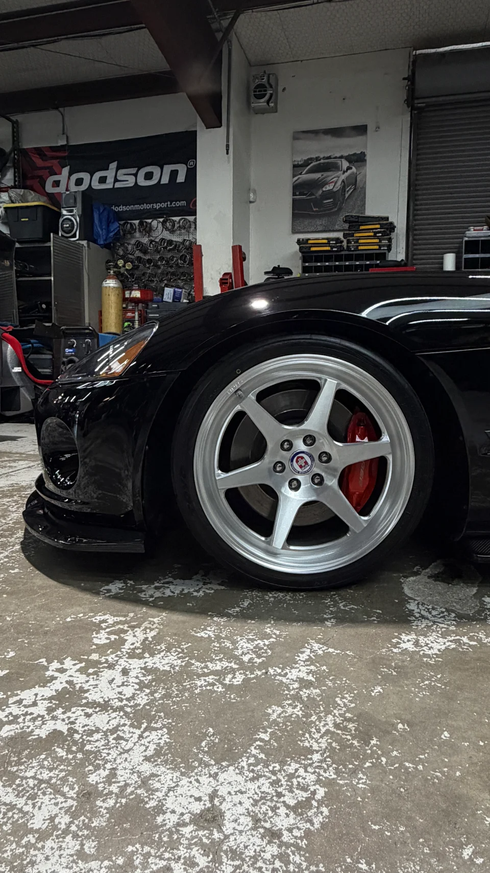 Black Dodge Viper with HRE wheels and red brake calipers in a performance tuning shop.