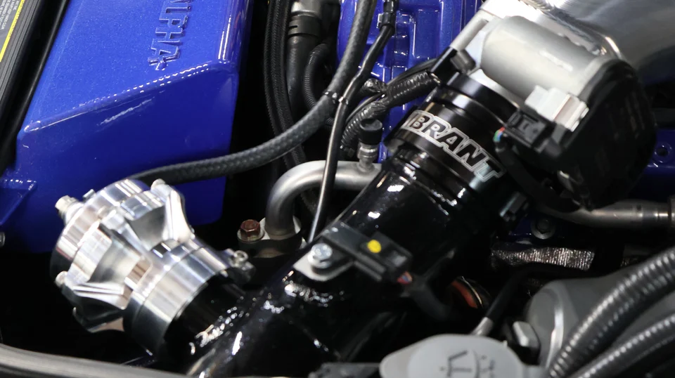 Close-up of a high-performance engine bay featuring an Alpha Performance intake manifold, Vibrant boost pipe, and blow-off valve.