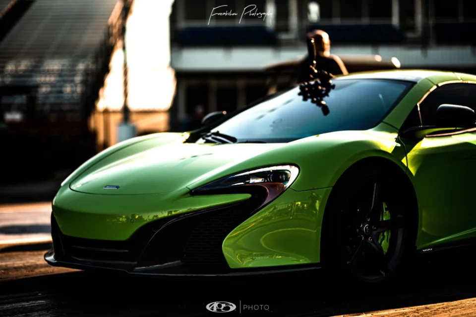 A vibrant green McLaren supercar captured in a professional photoshoot setting, highlighting its sleek front design.