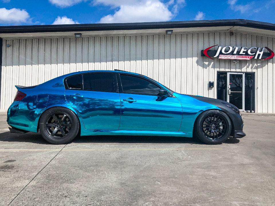 A blue and teal chrome wrapped Infiniti G35 sedan with aftermarket wheels parked outside Jotech Motorsports.