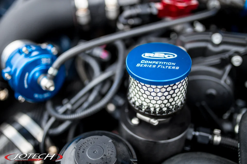 Close-up detail of a performance engine bay featuring a blue RBC Competition Series air filter and a blue blow-off valve.
