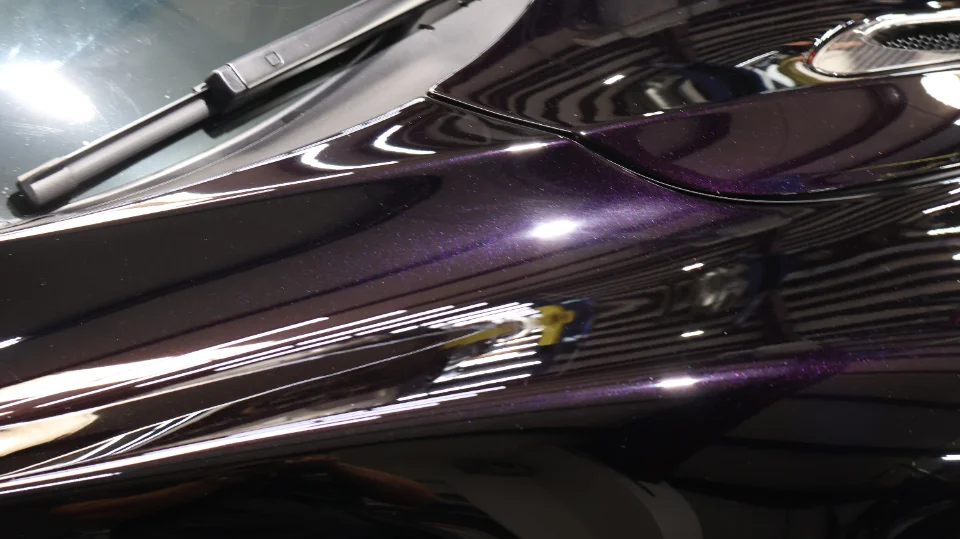 Close-up detail of a McLaren's metallic purple paint on the fender, showcasing reflections and the car's finish.