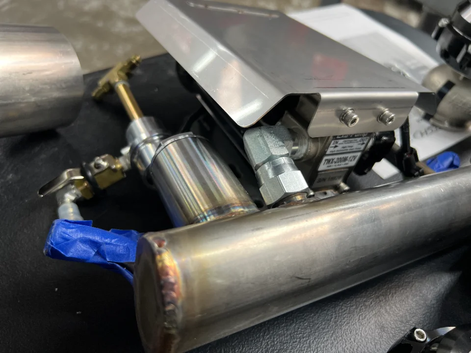 Close-up of a water methanol injection system with stainless steel piping and solenoid valve.