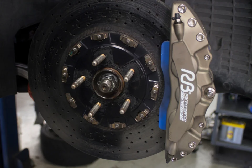 Close-up of a high-performance R3B Performance brake caliper and drilled rotor on a vehicle in a shop.