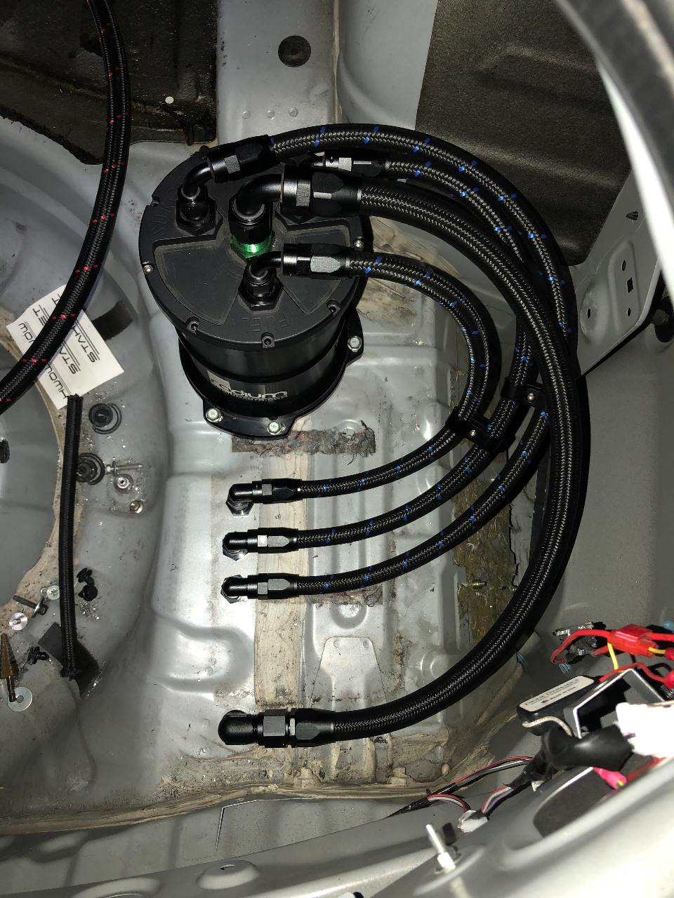 Radium Engineering fuel surge tank and braided lines installed in the trunk of a performance car during an upgrade.