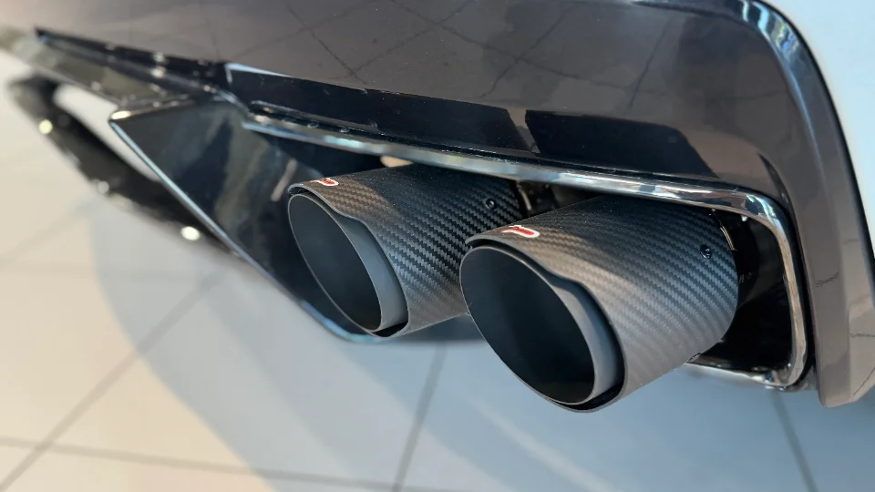 Close-up of carbon fiber exhaust tips integrated into the rear bumper of a performance car.