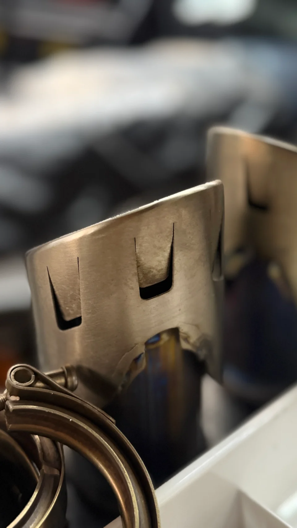 Close-up of titanium V-band clamps and exhaust components, showcasing fabrication detail for high-performance vehicles.