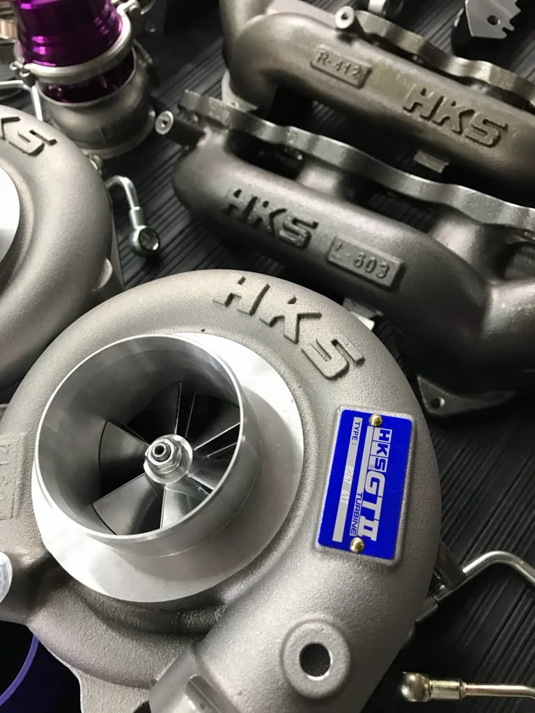 A close-up shot of multiple HKS GTIII turbochargers and turbo manifolds, highlighting the compressor wheels and brand labels.