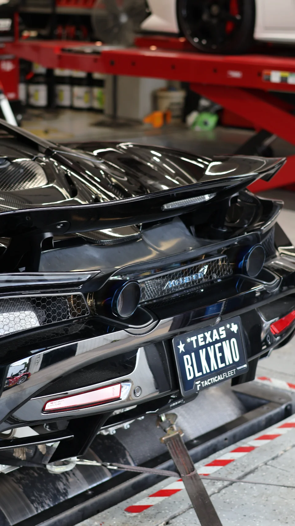 Rear view of a black McLaren supercar on a dyno, showcasing its custom exhaust tips and carbon fiber rear diffuser.