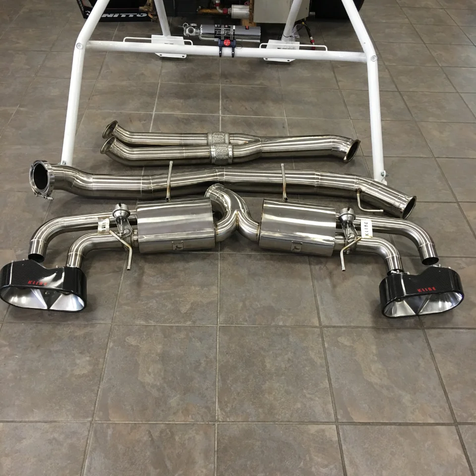 Kline Innovation stainless steel exhaust system with carbon fiber tips laid out on a tiled floor, ready for installation.