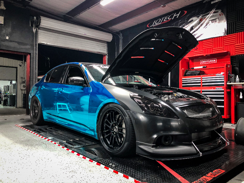 Infiniti G37 sedan with a blue chrome wrap and custom front bumper on a dyno at Jotech Motorsports.