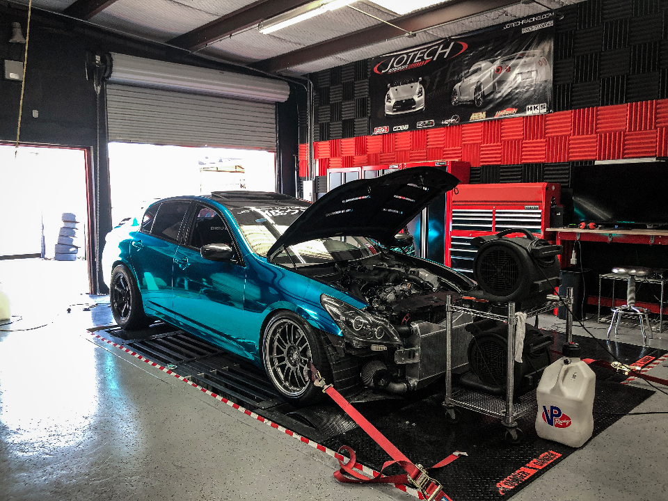 Teal chrome wrapped Infiniti G37 sedan on a dynamometer at Jotech Motorsports for performance tuning and power measurement.