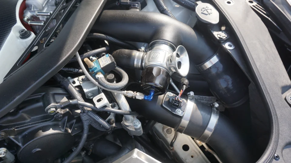 A close-up of an aftermarket blow-off valve and boost piping in a performance car's engine bay.