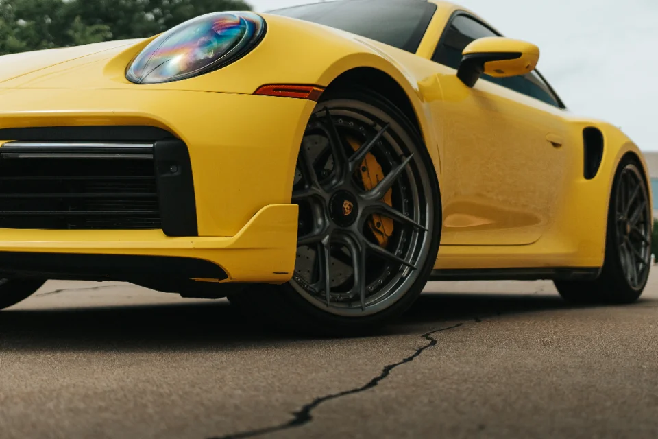 Low angle shot of a yellow Porsche 911 with custom multi-spoke wheels and yellow brake calipers.