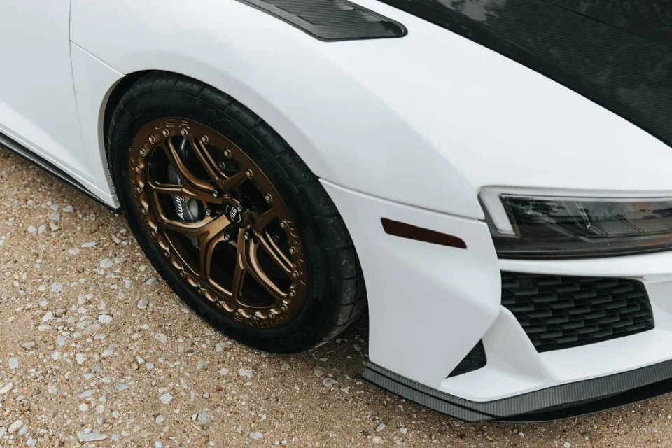 A white Chevrolet Camaro with bronze BBS wheels, Audi Sport brakes, and a carbon fiber front splitter.