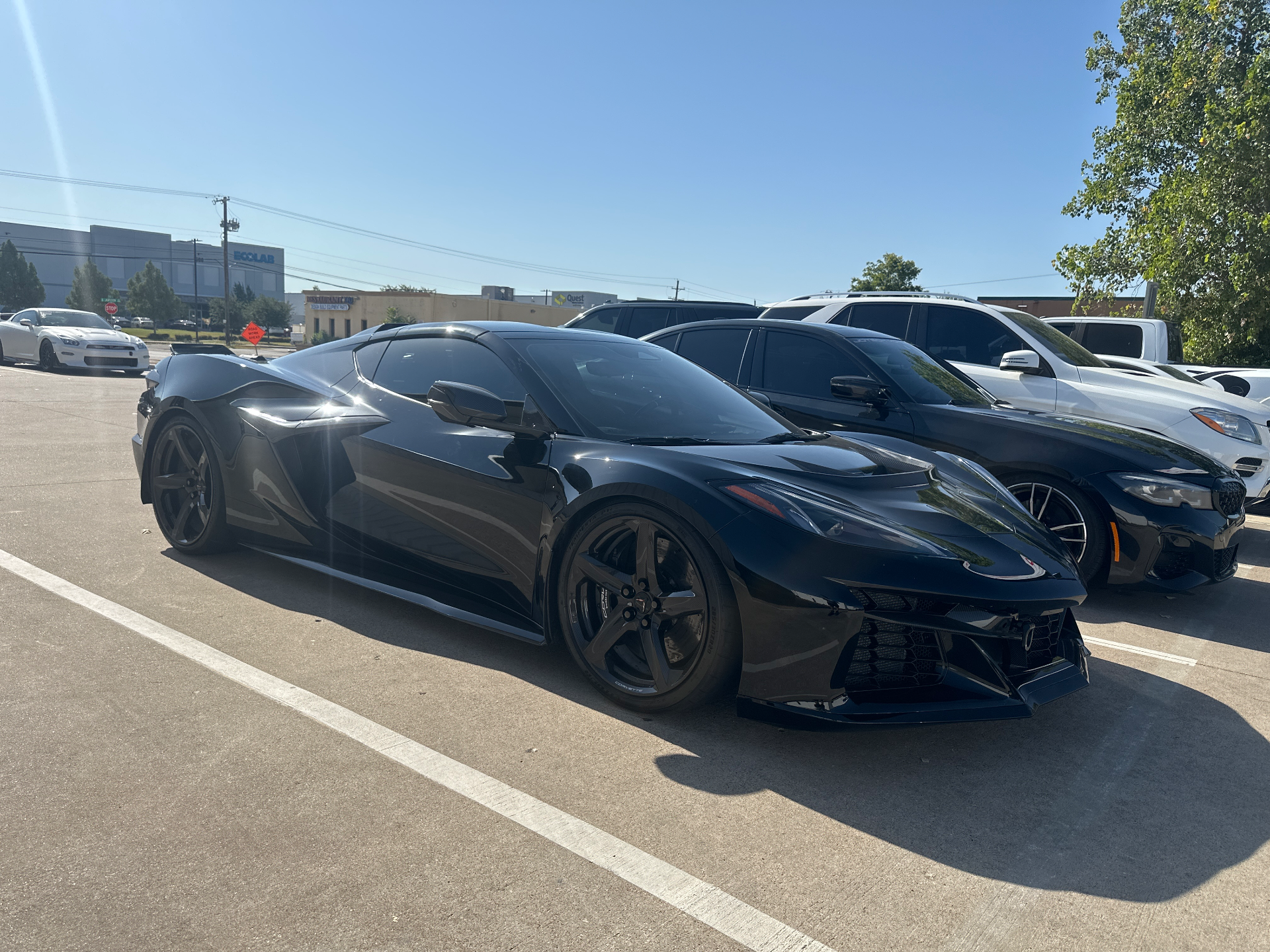 A black Chevrolet Corvette C8 Z06 parked outdoors on a sunny day, with other cars in the background.