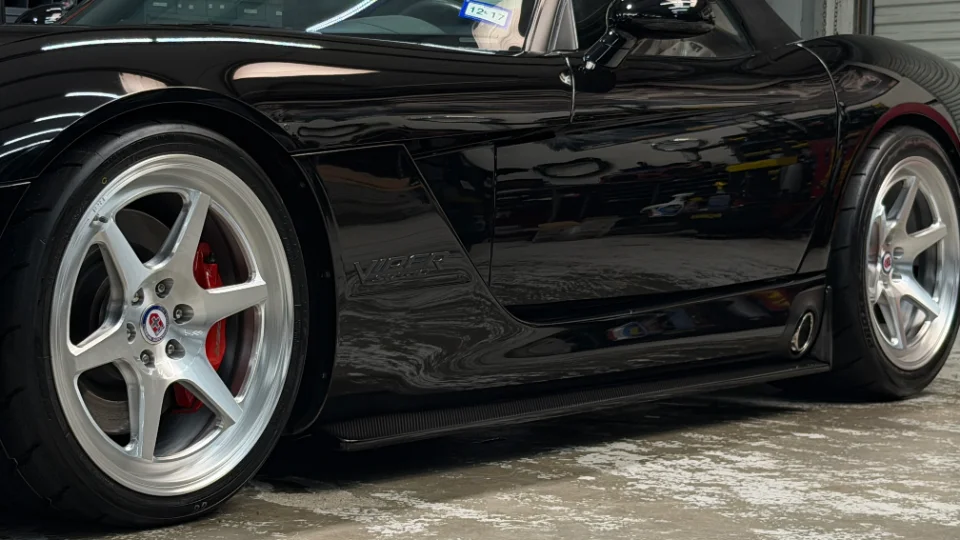 Close-up of a black Dodge Viper showing custom HRE wheels, red brake calipers, and side exhaust.