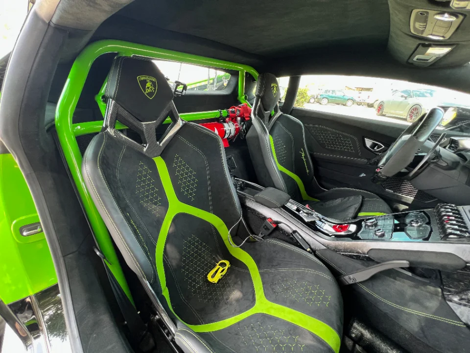 Lamborghini Huracan interior with bright green roll cage, racing seats, and a fire extinguisher, showcasing custom safety features.