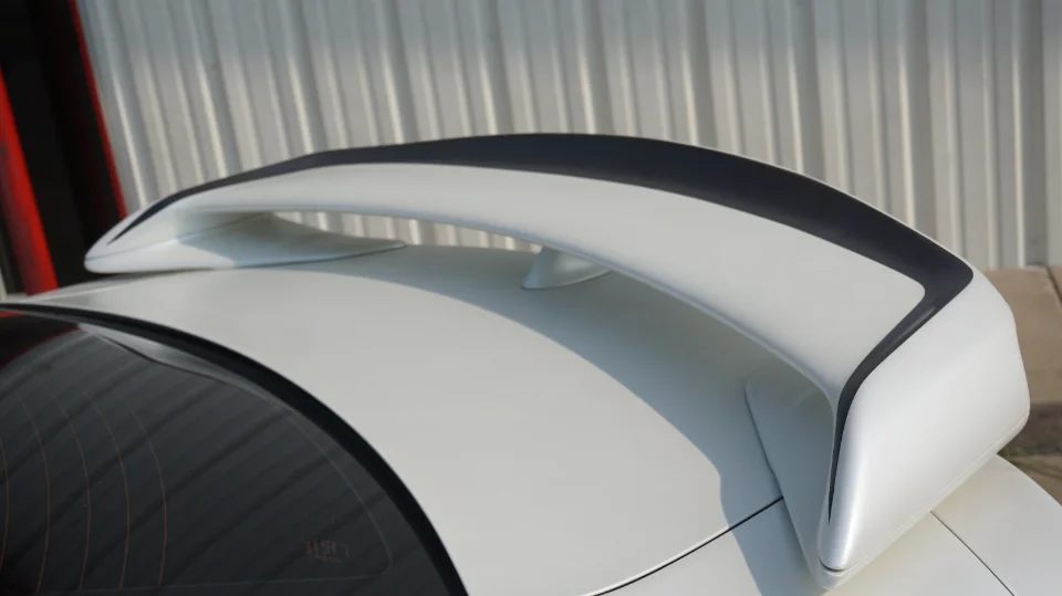 A close-up of a white car's rear wing with black accents.