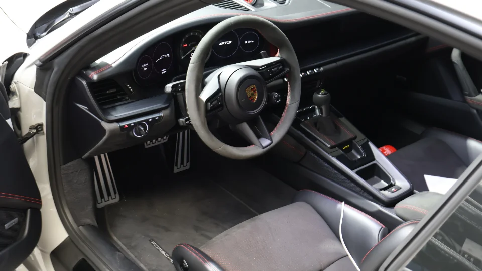 Interior view of a Porsche GT3, showing the steering wheel, sport seats, and aluminum pedals.