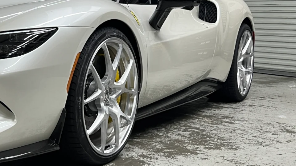 A white Ferrari with custom HRE wheels, yellow brake calipers, and a carbon fiber side skirt.
