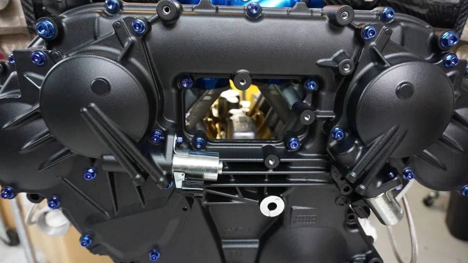 Close-up of a high-performance engine block with blue anodized bolts, showcasing detailed engine internals.