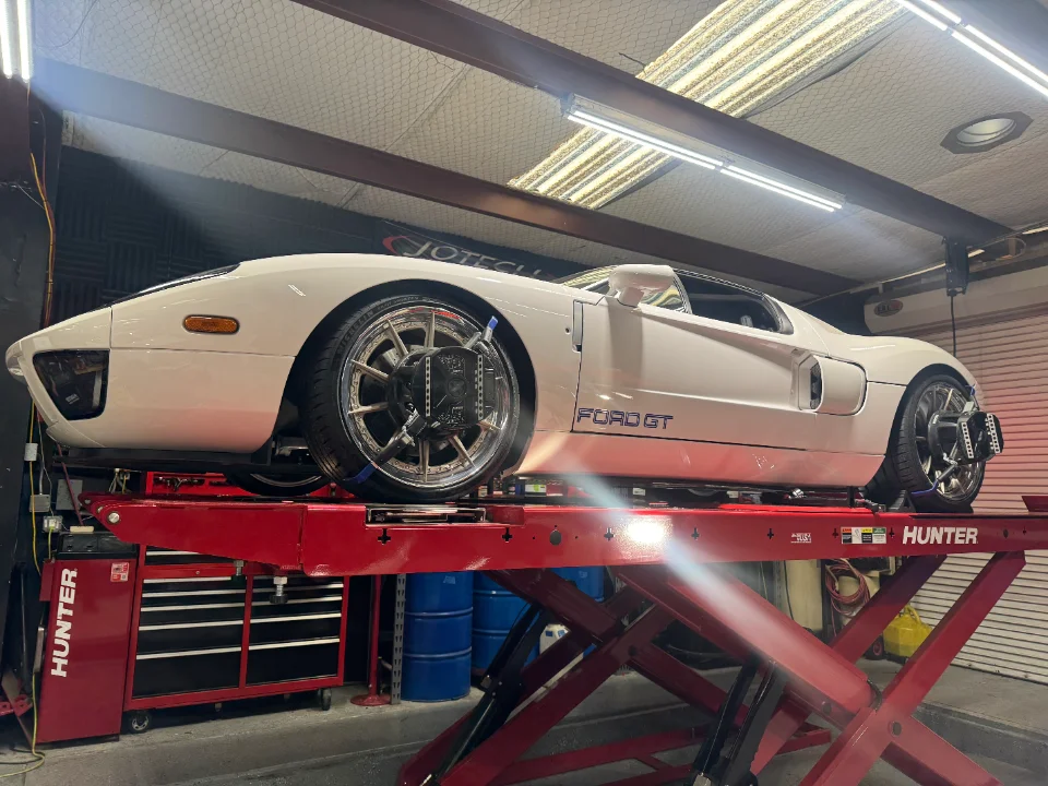White Ford GT supercar on a red Hunter alignment lift in a performance tuning shop.