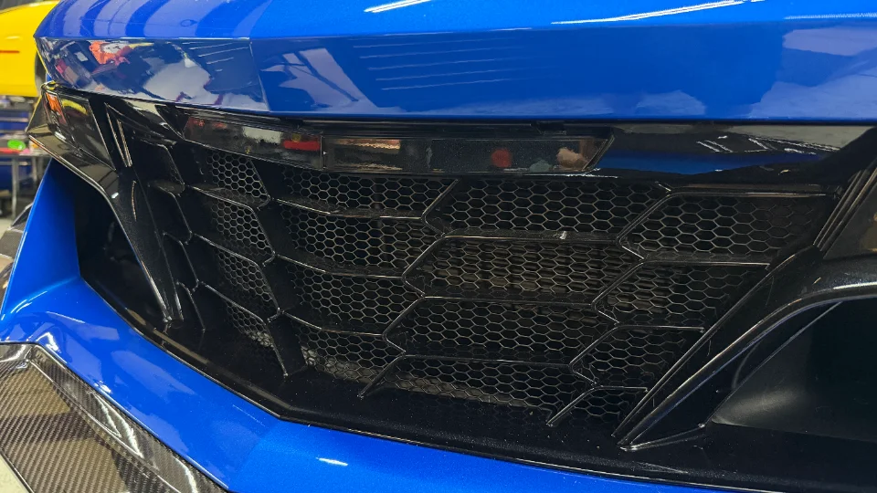 Close-up of the front grille and carbon fiber trim on a blue C8 Corvette.