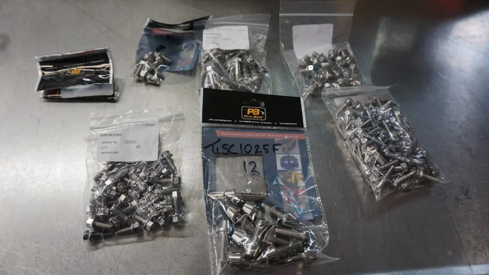 Bags of Pro-Bolt titanium and stainless steel fasteners and hardware on a metallic surface.