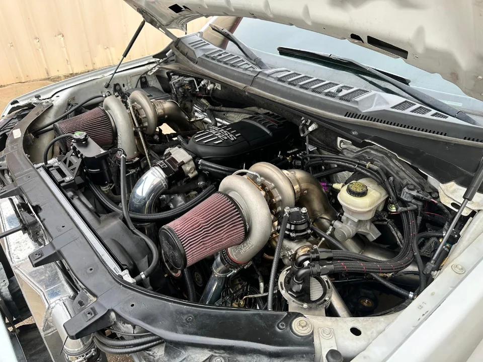 A detailed view of a twin-turbocharged engine bay in a Ford F-150, showcasing custom performance modifications.