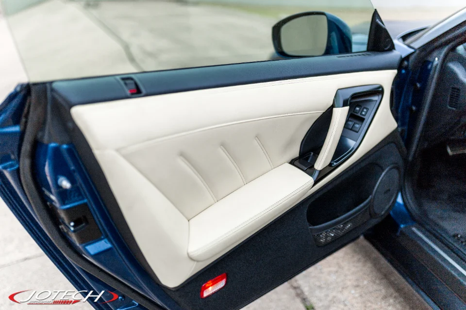 Detailed view of a Nissan GT-R R35 interior door panel with cream leather and black trim, customized by Jotech.
