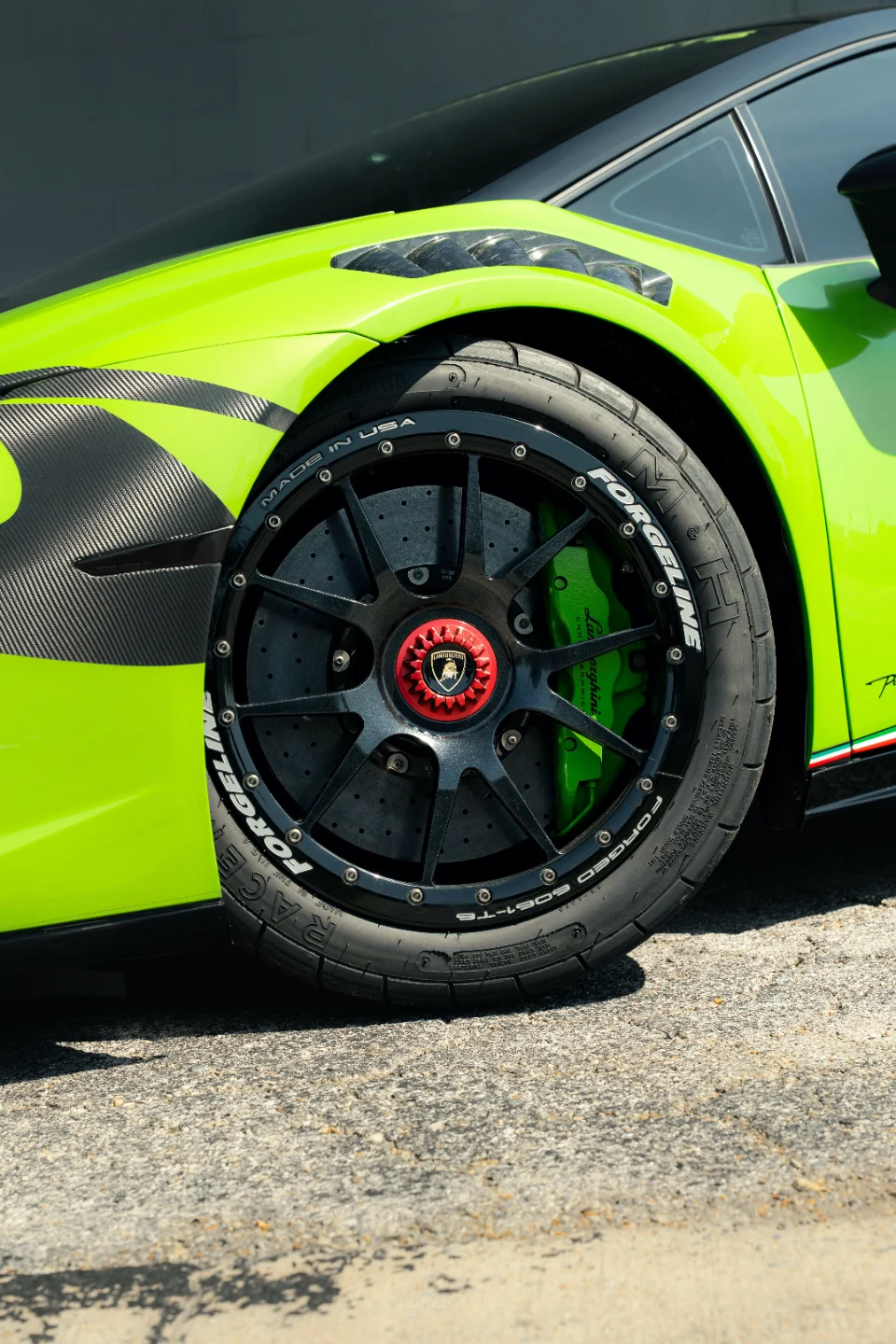 A close-up of a lime green Lamborghini Huracan's front wheel, featuring Forgeline wheels, performance tires, and green brake calipers.