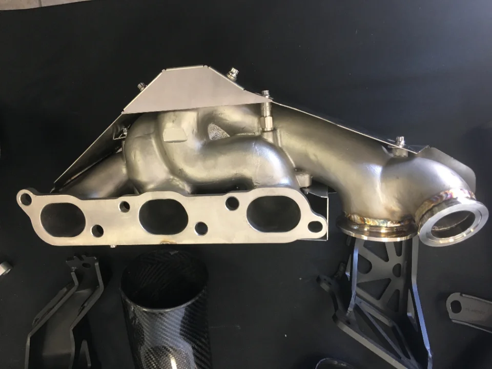 Stainless steel turbo exhaust manifold with a heat shield, a high-performance automotive part.