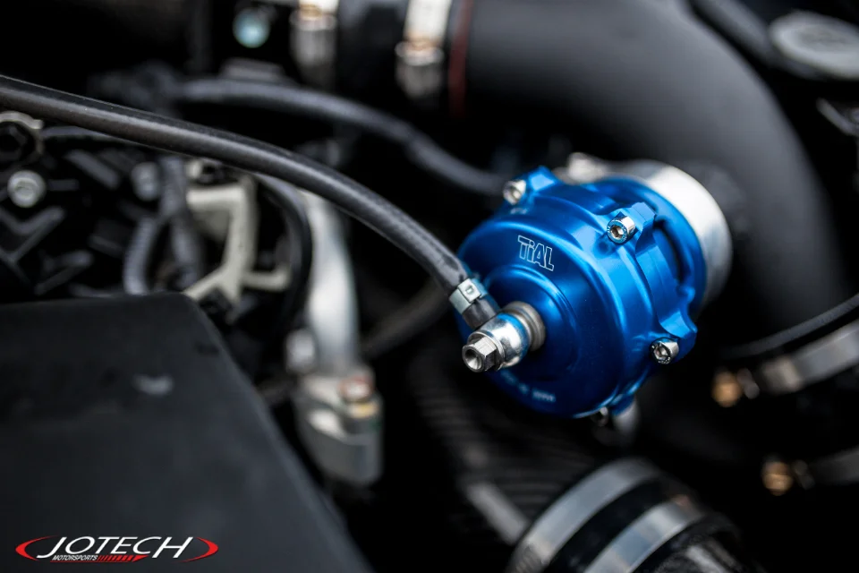 Close-up of a blue TiAL blow-off valve installed in a performance car's engine bay.