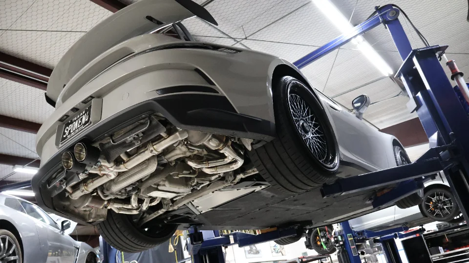 A Porsche 911 GT3 RS on a lift in a performance shop, showcasing its aftermarket exhaust system and undercarriage.
