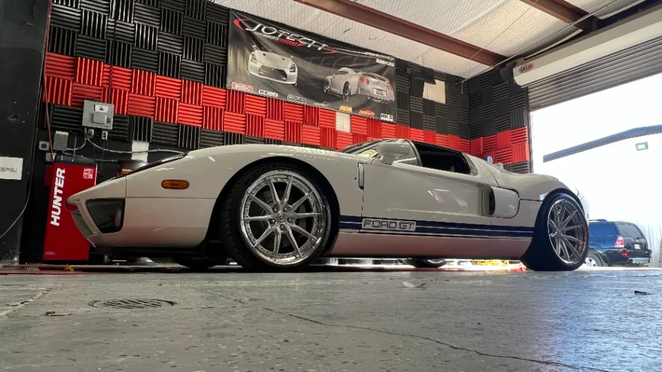 White Ford GT strapped to a dynamometer at Jotech Motorsports performance tuning shop, ready for a power run.