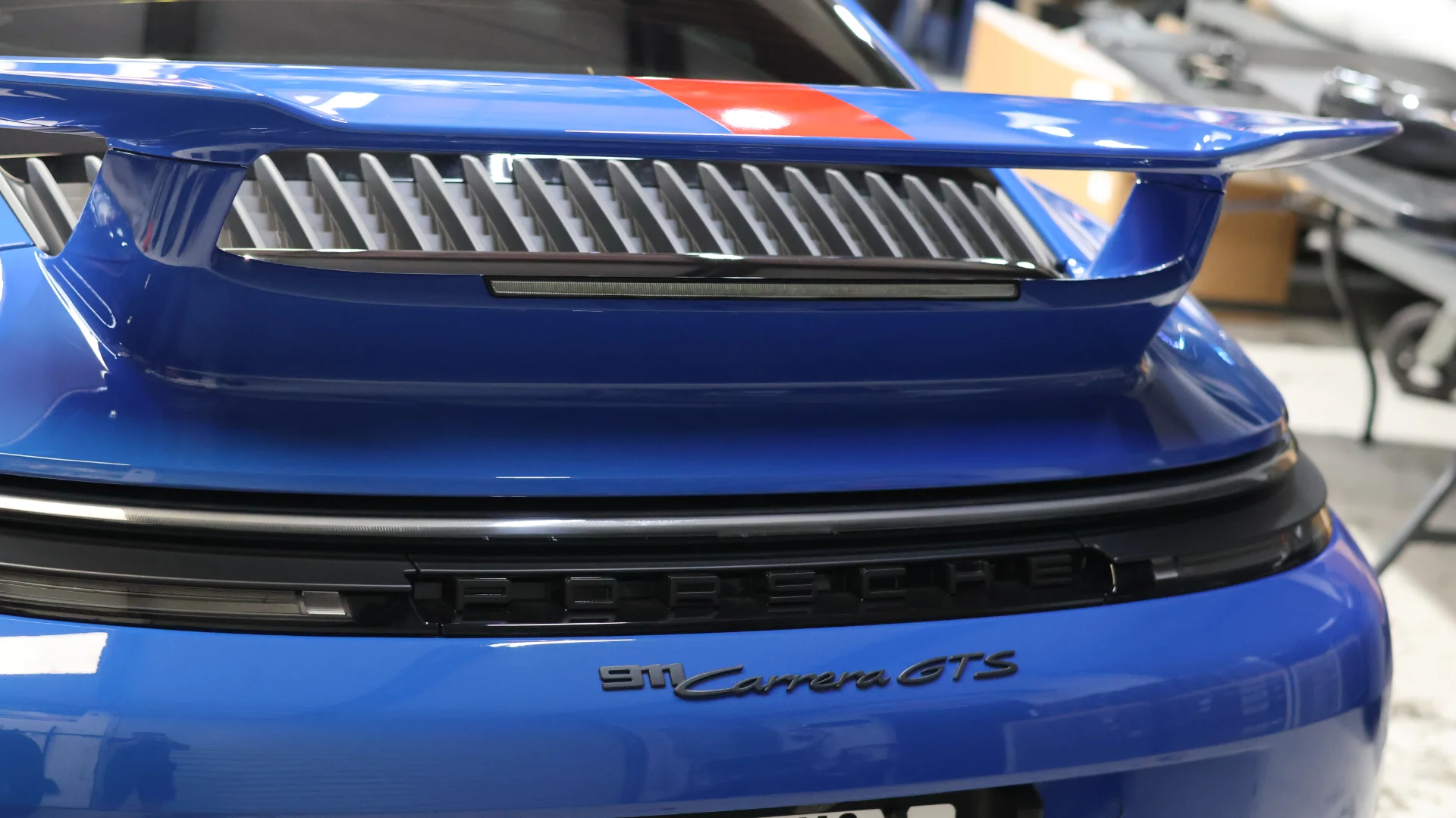 Rear view of a blue Porsche 911 Carrera GTS showcasing its distinctive rear wing and badging.
