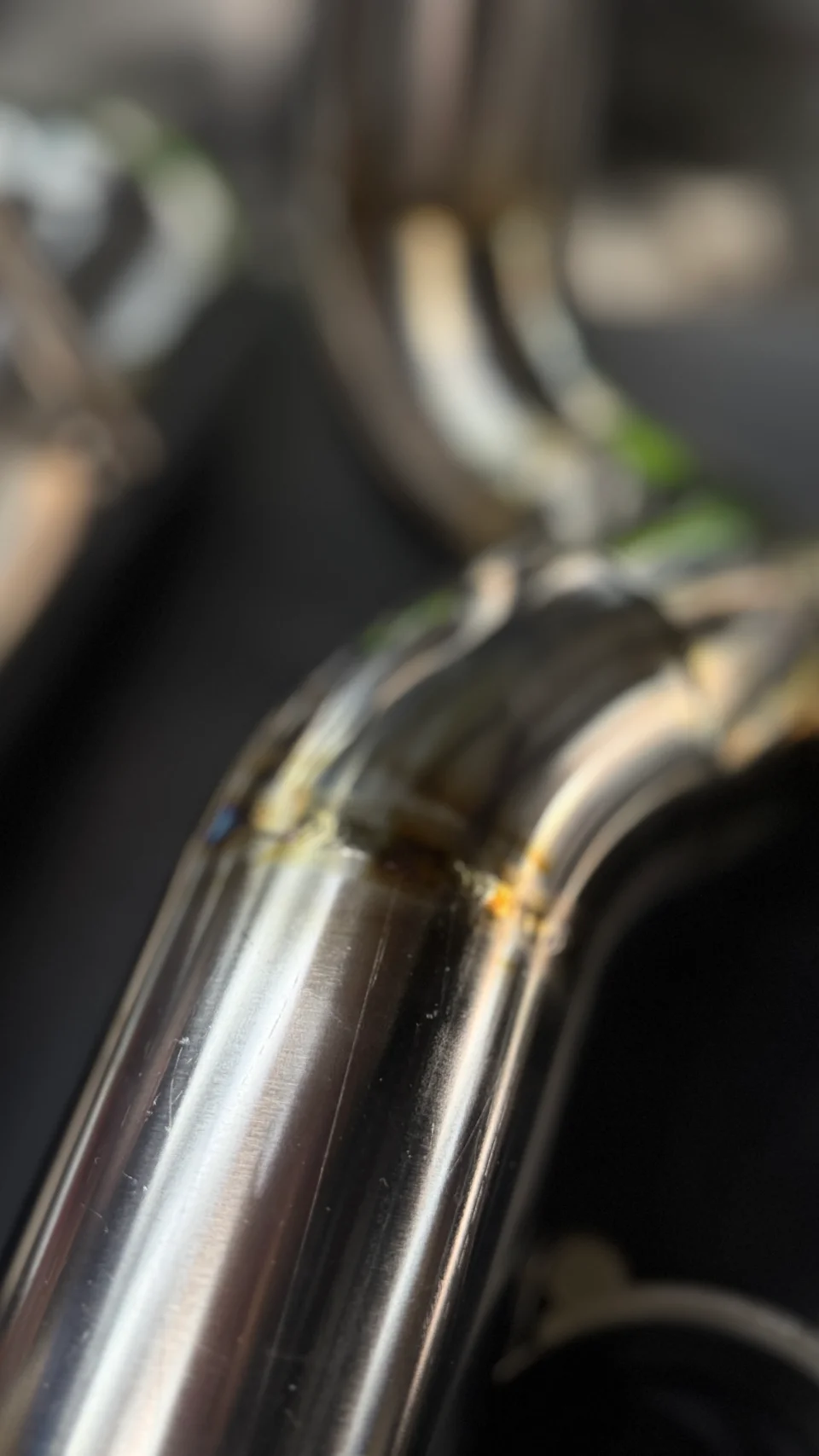 Close-up detail of a stainless steel exhaust pipe with a visible weld, showcasing craftsmanship.